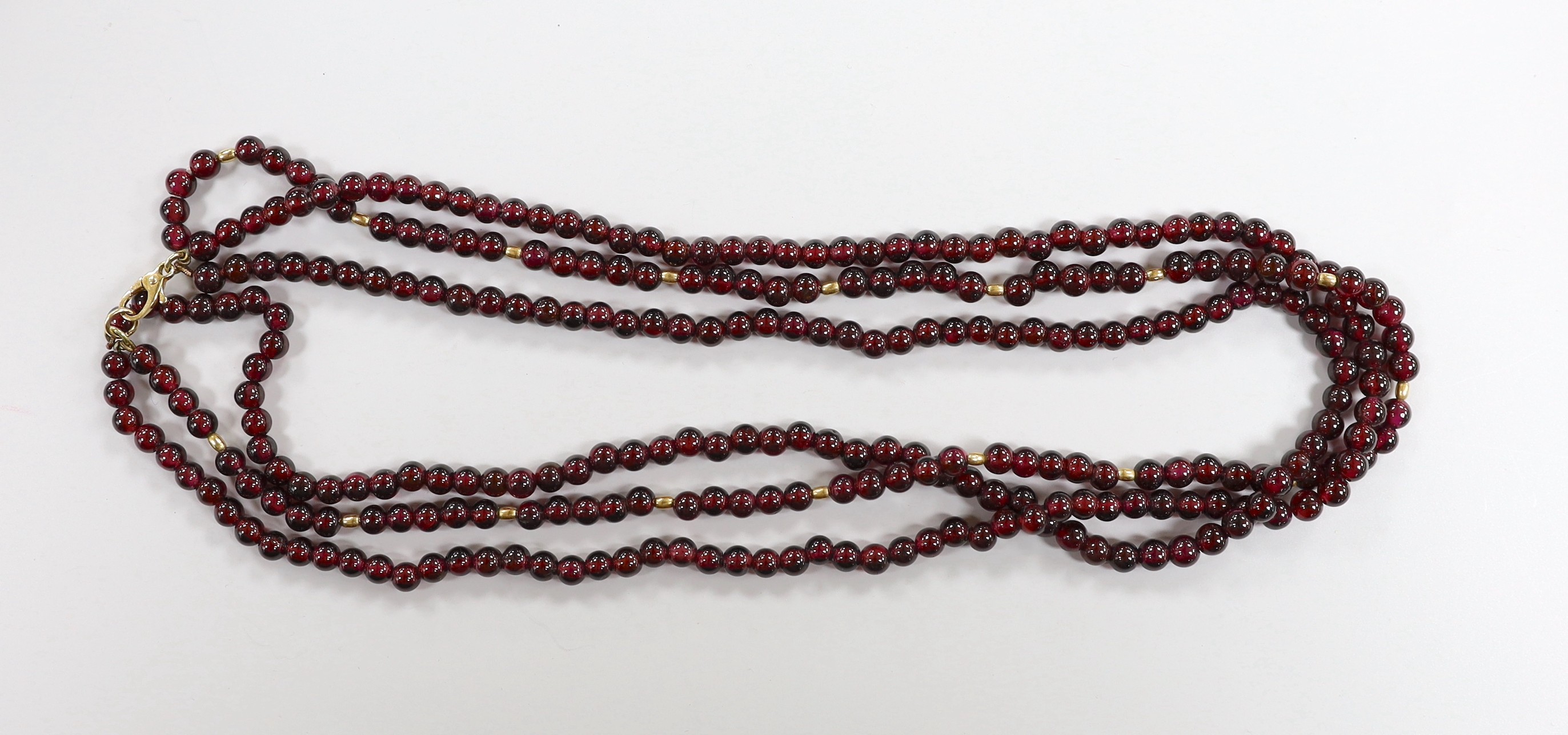 A Tiffany & Co triple strand garnet bead necklace, with 750 clasp and spherical spacers, 48cm, in a Tiffany & Co box.